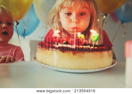 happy little girl make wish blow candles at birthday party