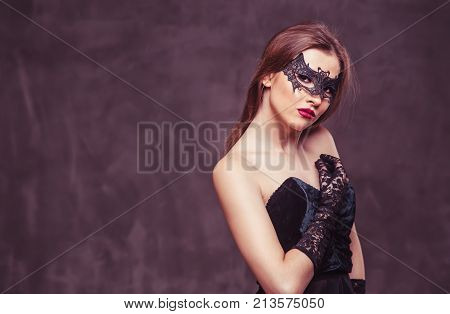 Portrait of sexy attractive brunette woman wears black mask on grey studio background with copyspace