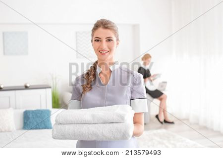 Beautiful chambermaid with towels in room