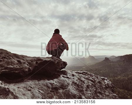 Sitting Hiker On Rock.  Man In Red Black  Warm Clothes Is Sitting On Cliff And Enjoying Far View.