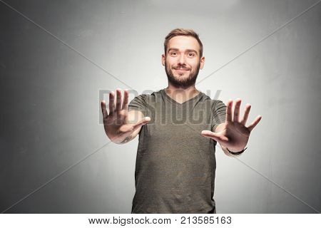 Young man streeking his arms with open palms, looking defensive. 'No' sign. 'Stop' gesture.