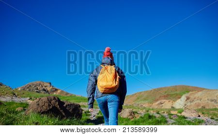 back view of woman traveler on a walk in the Valley of the river of Hveragerdi Iceland. Hiking Tour of Reykjadalur Hot Springs