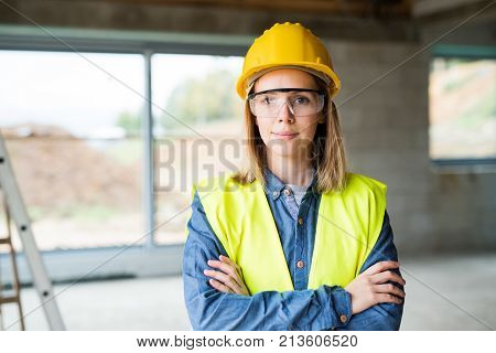 Female worker on the construction site. Beautiful young woman with crossed arms.