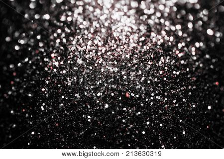 Black glitter sparkle background with red inclusion. Black friday shiny pattern with sequins. Christmas glamour luxury pattern, black christmas and glitter diamond background. Dark silver black friday pattern