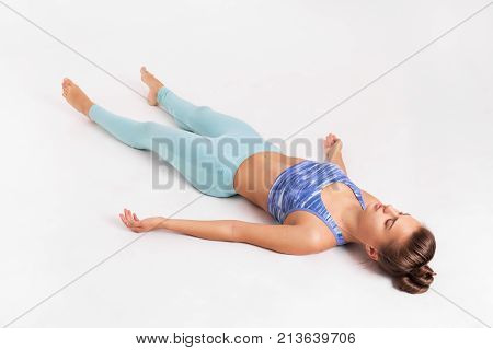 Young athletic girl lies after training. Yoga and meditation. Shavasana. Poses and asanas. The girl is lying on the floor.