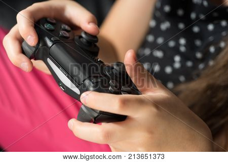UFA RUSSIA - NOVEMBER 12 2017: Hand girl playing Sony Dualshock 4 controller for PlayStation 4 pro. Sony PlayStation 4 pro game console of the eighth generation.