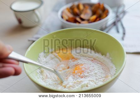 Cooking plum clafoutis from flour, eggs, and fruits