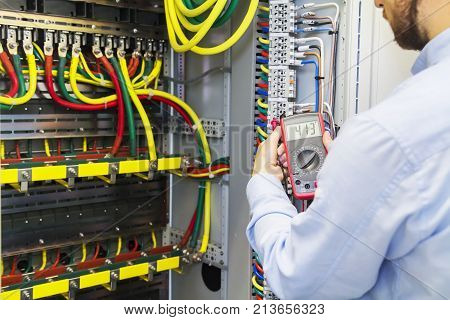 Engineer tests power high voltage three phase circuit box with multimeter. Electric service power system. Support electrician in fuse panel