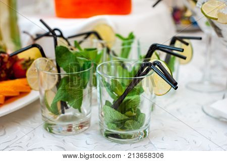 Fresh fruits and berries of different bright colors cut in small pieces are served on a table with mohito cocktail