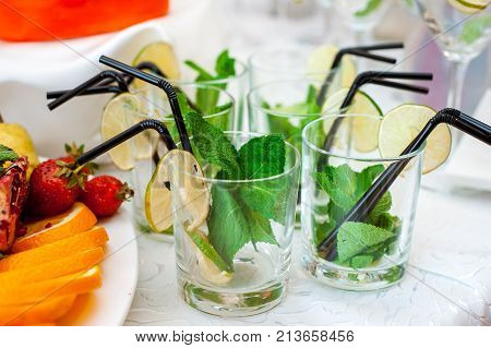 Fresh fruits and berries of different bright colors cut in small pieces are served on a table with mohito cocktail