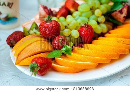 Fresh fruits and berries of different bright colors cut in small pieces are served on a table