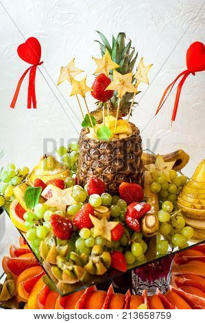 Fresh fruits and berries of different bright colors cut in small pieces are served on a table