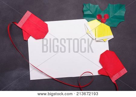 Origami mitters and Christmas bells on blank peace of paper on black boardschool background