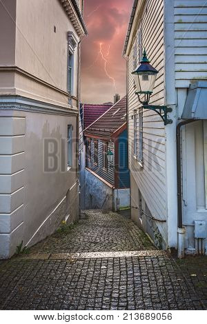 Narrow cobble stoned streets between old white traditional houses in the old part of Bergen town, Norway