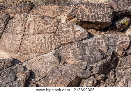 Petroglyphs etched in the brown rocks in the desert in Arizona