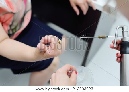 The dermatologist removes the wart on the patient's finger using a special device - a cryodestructor
