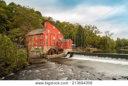 The historic Red Mill in Clinton NJ with people fishing in the river. The village also decorated for halloween as photo taken in Mid October