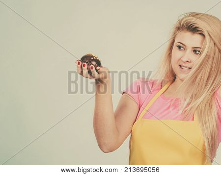 Diet sweets food concept. Woman holding delicious chocolate cupcake with peanut frosting about to take bite