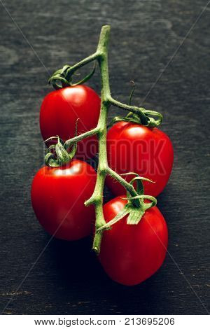 Fresh cherry tomatos on the black wooden board
