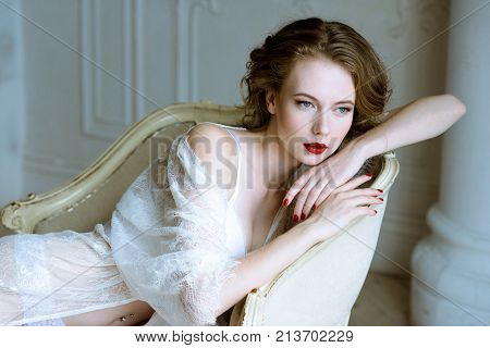 Fashionable female portrait of cute lady in white robe indoors. Close up beautiful sexy model girl in elegant pose. Closeup beauty brunette woman with hairstyle and makeup. Glamorous face with make up