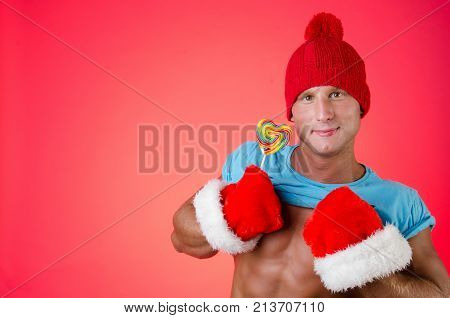 Sweet sexy guy. Candy and holidays. Christmas and sexy naked man. Red background.