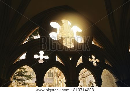 Gothic Arck Decorated Window To A Church Yard With A Cathedral At The Background And Evening Light S