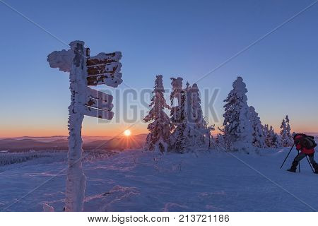 Tourist signpost mountain top Lusen covered by large ice. View of the snowy mountain peaks view from Lusen in Bavaria in the morning sun.