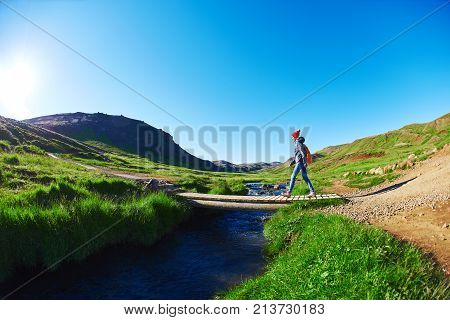 woman traveler with small orange backpack on a walk in the Valley of the river of Hveragerdi Iceland. Hiking Tour of Reykjadalur Hot Springs