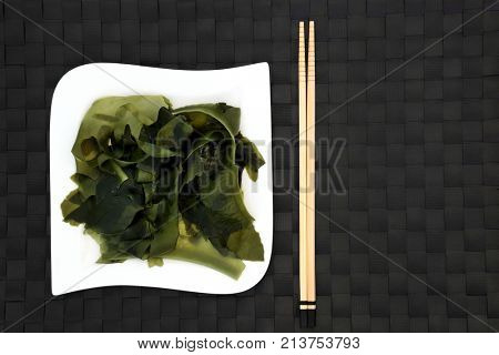 Japanese wakame seaweed food on a square porcelain plate with chopsticks. Has many health benefits and is very high in minerals.