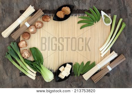 Macrobiotic diet food background with udon and sobu noodles, miso paste and vegetables on bamboo on marble foods high in protein, antioxidants, fibre and vitamins and minerals. Top view.