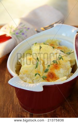 Картофель гратен dauphinoise на сковороде на деревенском фоне