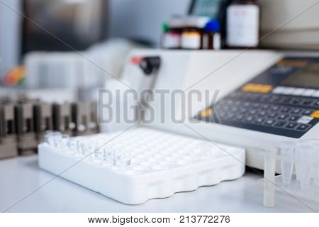 More samples. Empty little glass test tubes desire for being used while surrounded by medical appliances and situated on the white surface