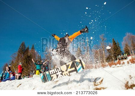 Bukovel, Ukraine - December 22, 2016: Man boarder jumping on his snowboard against the backdrop of mountains, hills and forests in the distance at Bukovel, Ukraine, Carpathian mountains on December 22, 2016