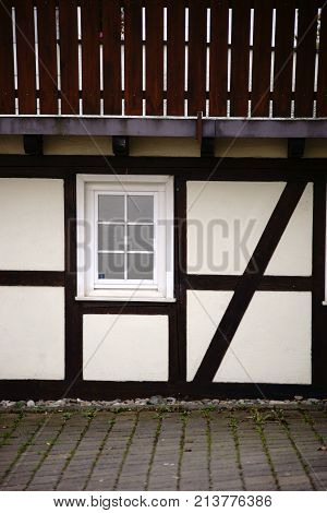 The beam construction and the wooden framework of a half-timbered house with a wooden railing.