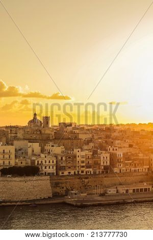 malta valletta . capital at sunrise with golden sky, clouds , harbor and boats. Old historical city