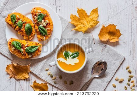 Pumpkin cream soup. Vegan healthy food. Breakfast or brunch on white wooden background.