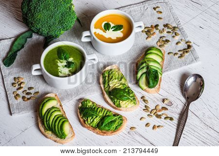 Vegetarian healthy food. Soup and vegan sandwiches. Different sandwiches with avocado. Brunch on white wooden background.