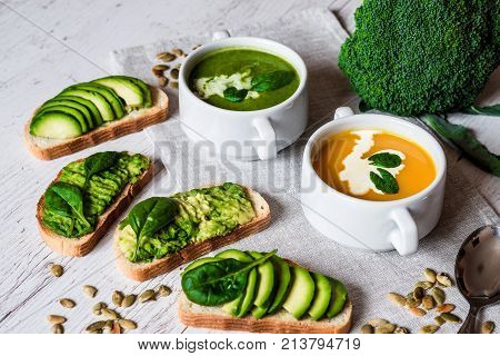 Vegetarian healthy food. Soup and vegan sandwiches. Different sandwiches with avocado. Brunch on white wooden background.
