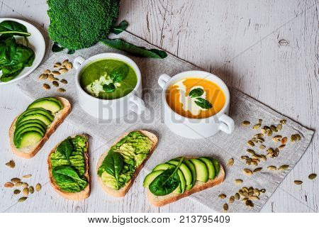 Vegetarian healthy food. Soup and vegan sandwiches. Different sandwiches with avocado. Brunch on white wooden background.