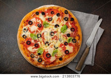 Pizza margarita with tomatoes mazarella and slices of olives on a dark concrete or stone background. Traditional Italian cuisine. Selective focus. Top view.