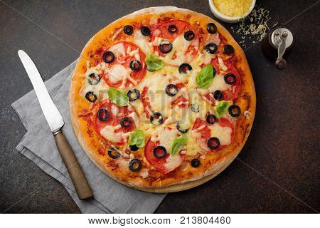 Pizza margarita with tomatoes mazarella and slices of olives on a dark concrete or stone background. Traditional Italian cuisine. Selective focus. Top view.