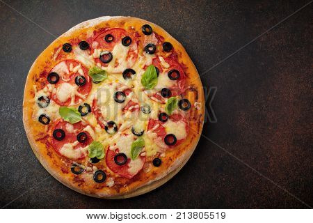 Pizza margarita with tomatoes mazarella and slices of olives on a dark concrete or stone background. Traditional Italian cuisine. Selective focus. Top view.