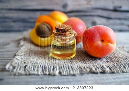 Apricot oil from apricot kernels in a glass jar and fresh ripe apricots on old wooden table.Essential apricot kernel oil for spa,beauty treatment,aromatherapy and bodycare. Selective focus.