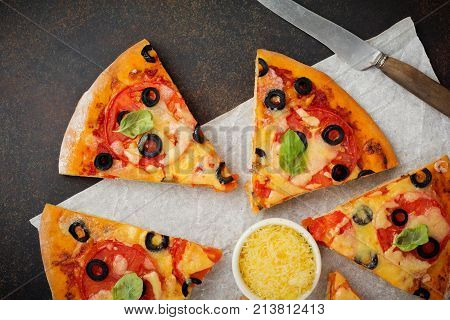 Pizza margarita with tomatoes mazarella and slices of olives on a dark concrete or stone background. Traditional Italian cuisine. Selective focus. Top view.