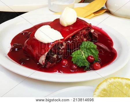 A fresh slice of cherry pie with cherry jam on a white plate. Close up shot
