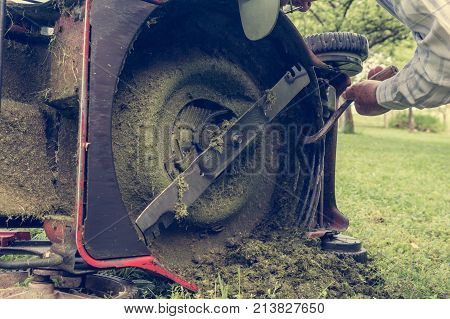 Man cleaning lawn mower blade. Preparing to mow some grass.