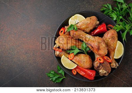 Fried chicken's pointed shanks in a cast-iron frying pan on a dark concrete or stone background. Selective focus.Top view.