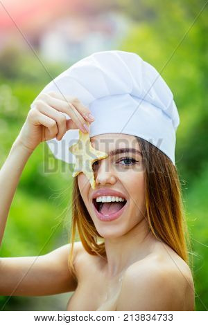 Happy woman in chef hat on summer day. Cooking and baking. Cook female with naked shoulders on nature. Healthy food and diet concept. Girl smiling with dough star.