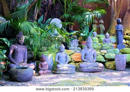 Buddha sculptures surrounded by lush green tropical plants taken on a patio in a Zen Meditation Garden