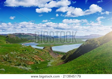 Travel to Iceland. road and river in a bright sunny mountain landscape. Vatna volcano covered with snow and ice on tne background.